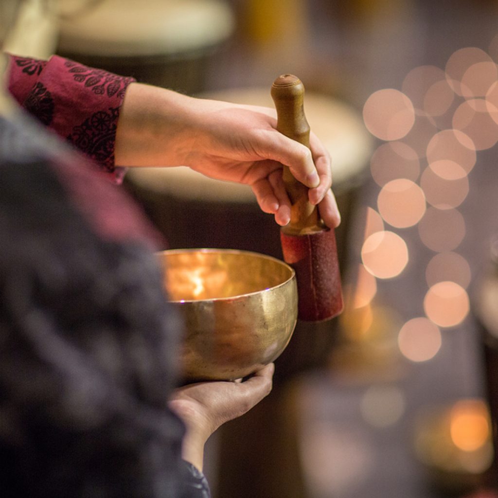 Woman playing on a tibetian singing bowl (shallow DOF; color ton